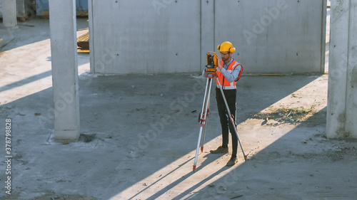 Construction Worker Using Theodolite Surveying Optical Instrument for Measuring Angles in Horizontal and Vertical Planes on Construction Site. Worker in Hard Hat Making Projections for the Building. © Gorodenkoff
