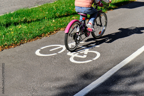 Obraz na płótnie The girl rides the pink bicycle on the bike path in autumn in sunny weather. w salonie