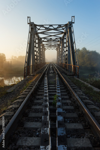 Landscape with railway and bridge. Sunrise over the misty river