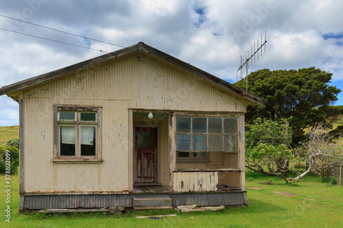 An old, abandoned corrugated iron house surrounded by green fields. Photographed on Urupukapuka Island, Bay of Islands, New Zealand