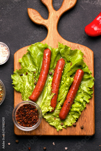 Vegetarian meat sausages baked with spices and sun-dried tomato on fresh herbs