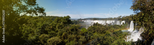 Large nature panorama of Iguacu  Iguazu  waterfall cascade on border of Brazil and Argentina. Amazing view of falls Cataratas in bright Sunny weather. Concept of travel. Copyright space for site