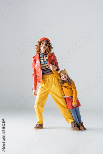 mother and daughter in colorful red and yellow outfits posing on grey background