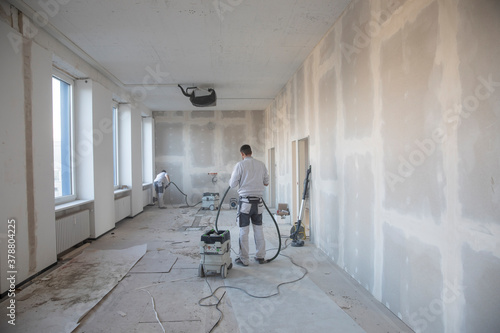 Handwerker schleift die Wände auf einer Baustelle