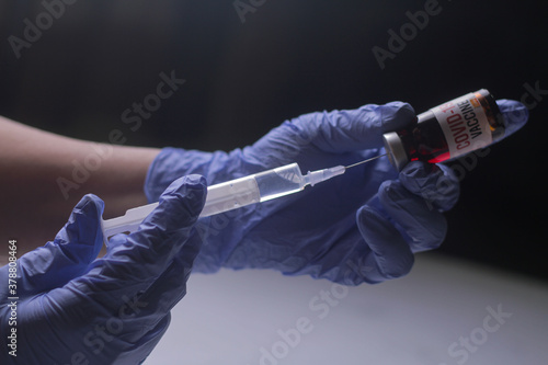 Doctor, nurse, scientist, researcher hand in blue gloves holding flu, measles, coronavirus, covid-19 vaccine disease preparing for human clinical trials vaccination shot, medicine and drug concept. 