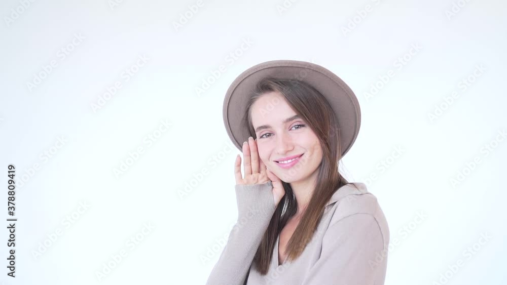 portrait of a young attractive fashion woman in a hat on a white background. Lady model isolated posing at camera in studio. Beauty in beige. The girl smiles and looks. Sexy with long hair and makeup portrait of a young attractive fashion woman in a hat on a white background. Lady model isolated posing at camera in studio. Beauty in beige. The girl smiles and looks. Sexy with long hair and makeup