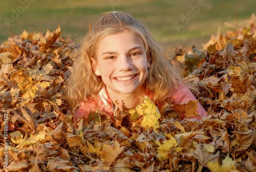 girl with big smile in pile of leaves