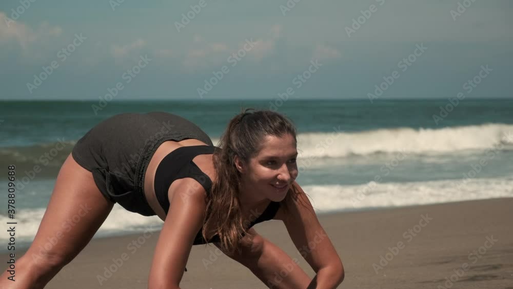 Alluring lady is stretching at sandy beach of an ocean