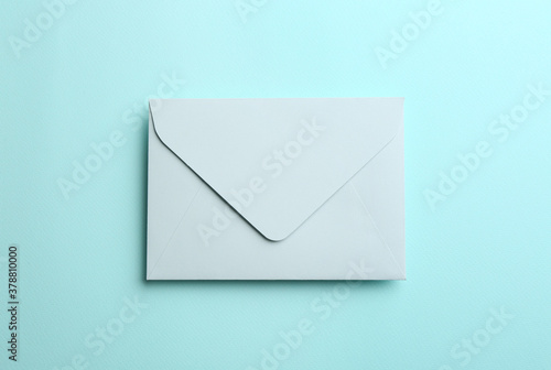 Paper envelope on light blue background, top view