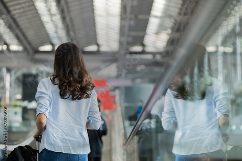 Asian traveler women standing on the sliding walkway in airport.