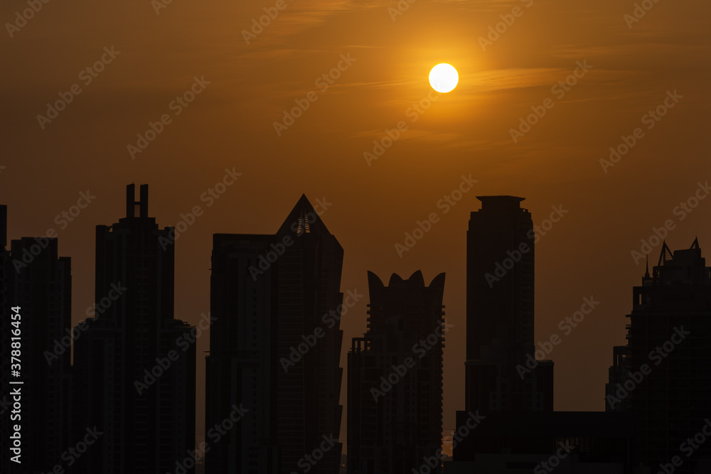 Dubai skyline at sunset with orange and yellow sky over the skyscrapers in the United Arab Emirates.
