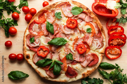pizza with salami bacon tomatoes pepper decorated with herbs