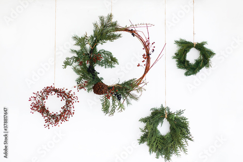 Creative different christmas wreaths with red berries and fir branches, isolated on white