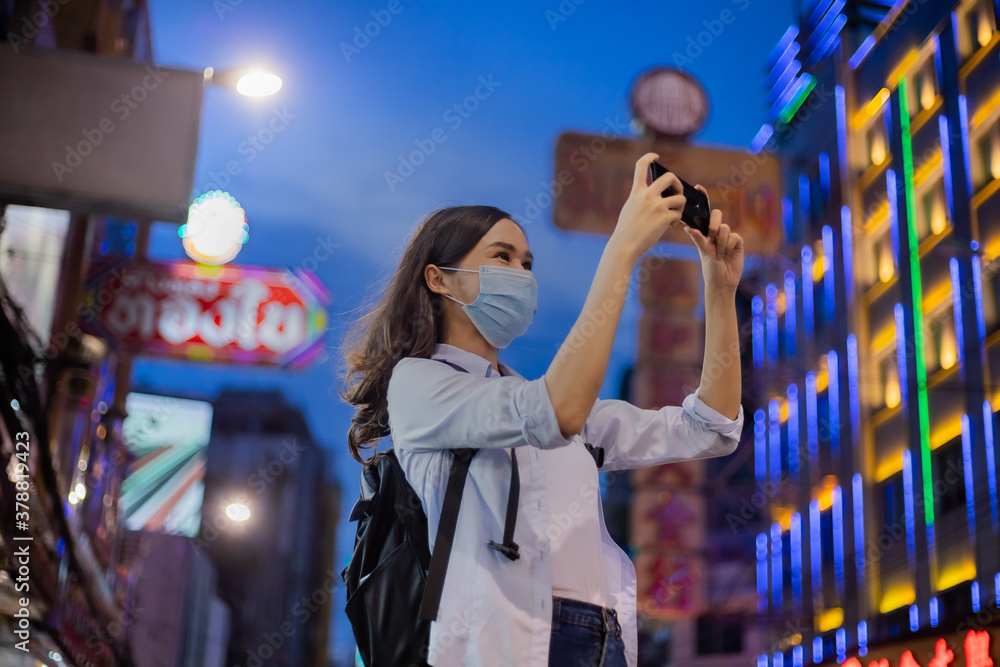Traveler women wear the mask  using smartphone to take a photo in chinatown.