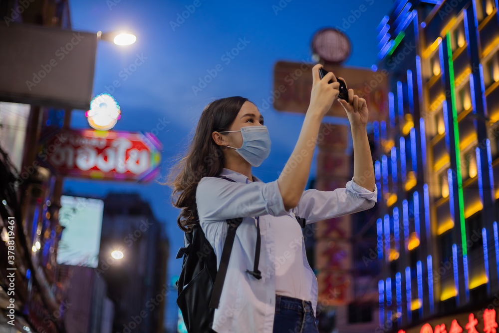 Fototapeta premium Traveler women wear the mask using smartphone to take a photo in chinatown.