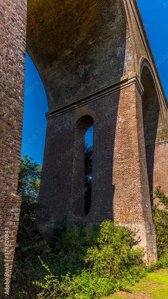 A view looking up towards an arch of the Chappel Viaduct near Colchester, UK in the summertime