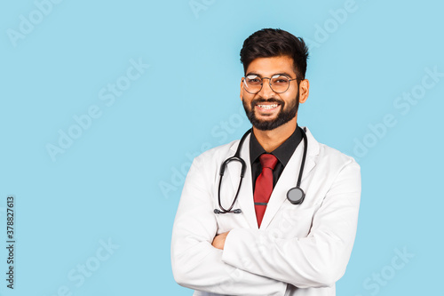 Cute Indian   Asian doctor wearing glasses with stethoscope  tie and white coat on light blue background.