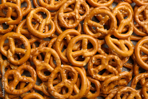 Many delicious pretzel crackers as background, top view
