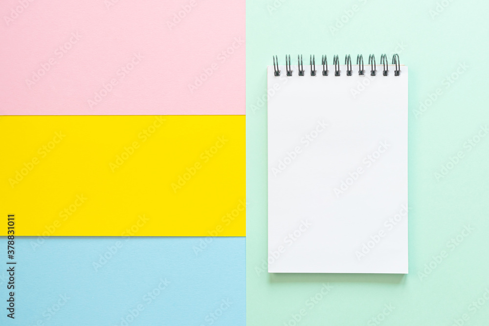 Spiral notebook with blank white sheet on multi-colored paper. The concept of office, school, creativity, learning. Top view, flat lay, copy space, minimalism. Pink, blue and yellow shades. Spiral notebook with blank white sheet on multi-colored paper. The concept of office, school, creativity, learning. Top view, flat lay, copy space, minimalism. Pink, blue and yellow shades.