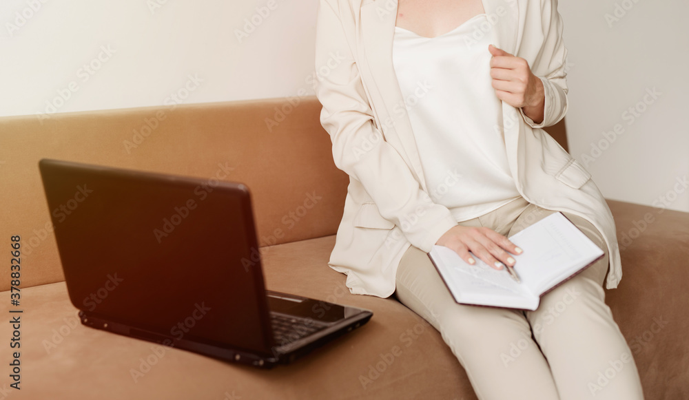 Naklejka premium Woman using laptop, sitting on the sofa, close-up photo of female hands, notebook and laptop