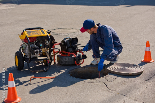 Plumber diagnoses a drain well on the street using special equipment.