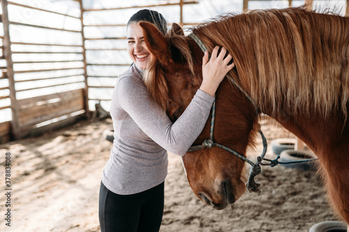 Εκτύπωση καμβά young woman hugs brown horse and laughs