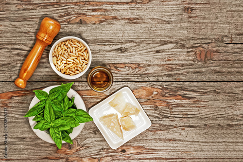 Fototapeta Naklejka Na Ścianę i Meble -  Ingredients for pesto. Top view of basil, pine nuts, garlic, parmesan and olive oil on wooden background