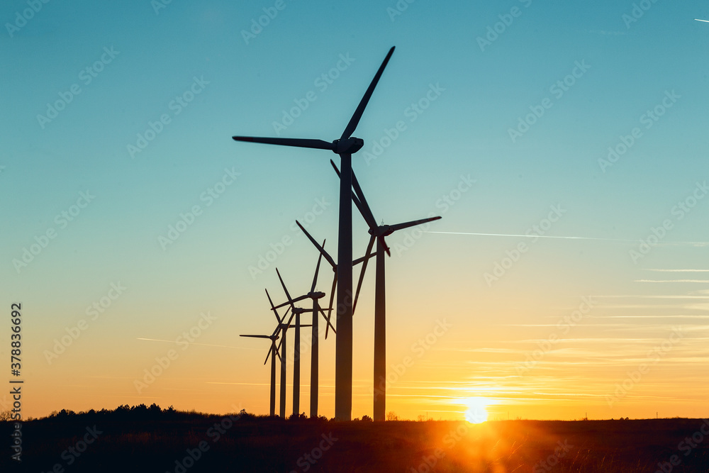 Wind Turbines at Dusk. Landscape sunset with windmills. Renewal source of electricity. Wind turbines field new technology for clean energy on mountain, sunset view with colorful twilight on sky. Wind Turbines at Dusk. Landscape sunset with windmills. Renewal source of electricity. Wind turbines field new technology for clean energy on mountain, sunset view with colorful twilight on sky.