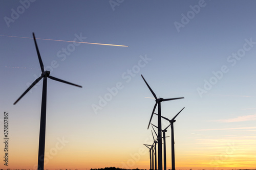Wind Turbines at Dusk. Landscape sunset with windmills. Renewal source of electricity. Wind turbines field new technology for clean energy on mountain, sunset view with colorful twilight on sky.