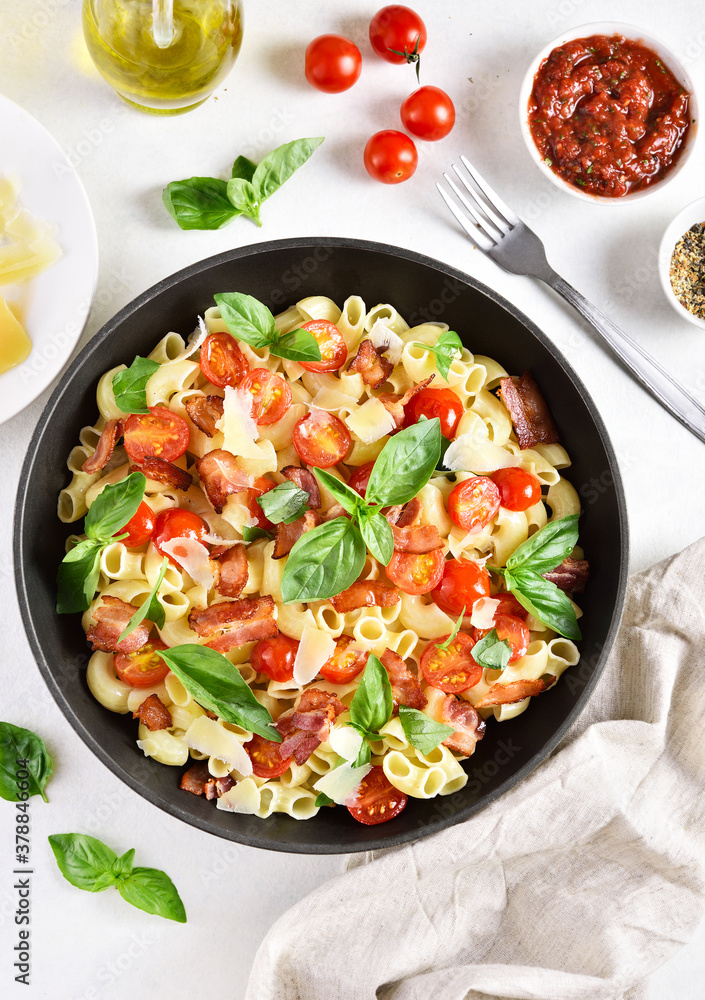 Tomato and bacon pasta with parmesan cheese and basil leaves