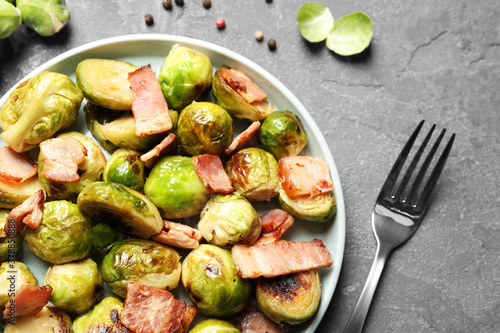 Delicious fried Brussels sprouts with bacon served on grey table, flat lay