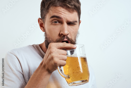 man with a mug of beer in his hands and a white t-shirt light background mustache beard emotions model