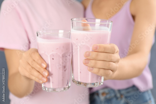 Women holding fig smoothie on grey background, closeup