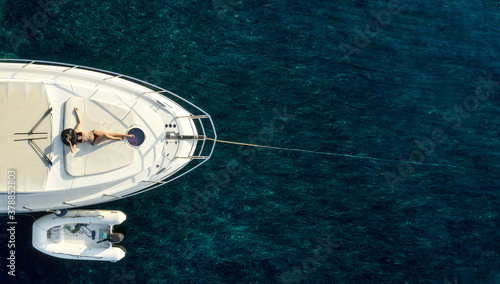 Directly above view at white luxury yacht with woman in swimsuit and hat laying on. Copy space
