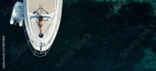 Aerial view at beautiful young woman relaxing on a private yacht deck in the sea. © 22Imagesstudio