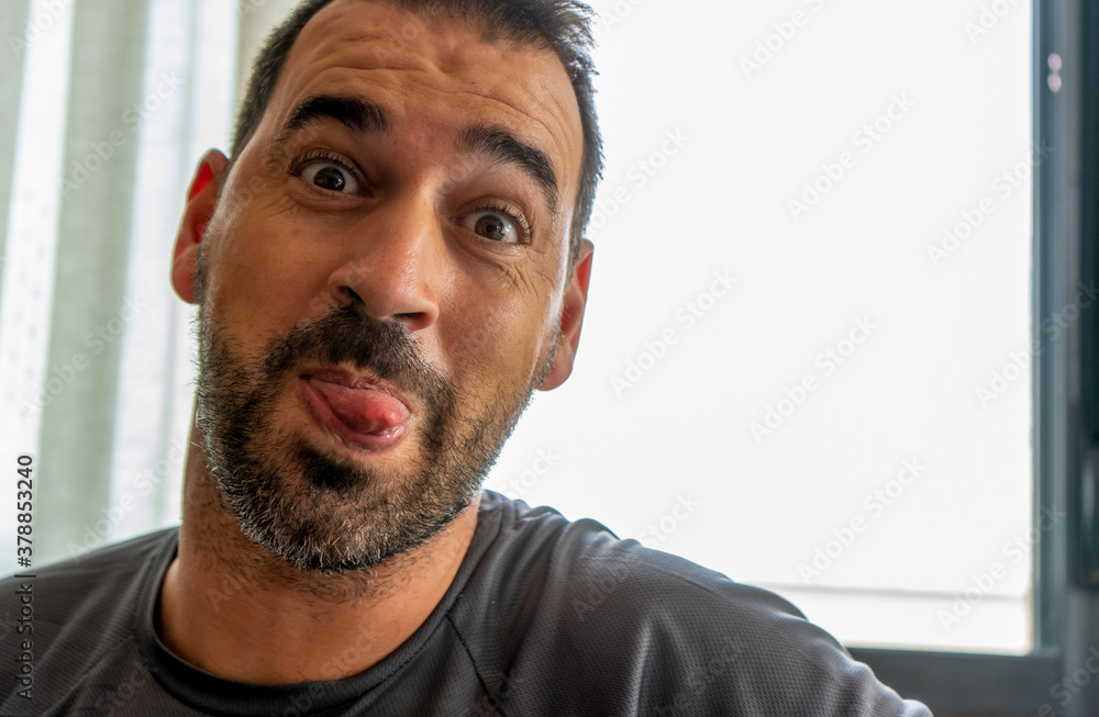 Fototapeta premium Portrait of middle-aged man with beard sticking out his tongue