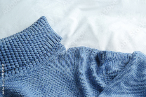 Stylish knitted sweater on white fabric, closeup