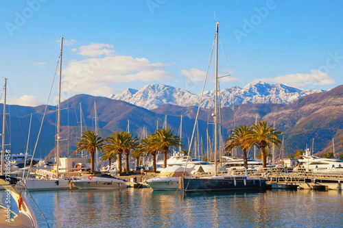 Beautiful winter Mediterranean landscape. Yacht marina at foot of snow-capped mountains. Montenegro, Tivat city. View of yacht marina of Porto Montenegro