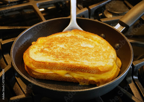 Grilled cheese sandwich being grilled in frying pan.