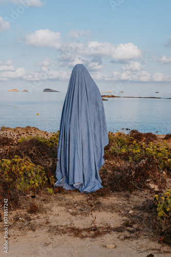 Woman in ghost costume standing on beach