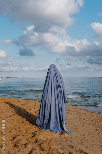Woman in ghost costume standing on beach