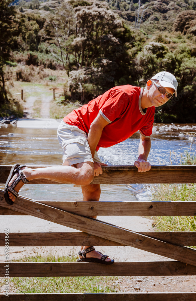 Mature man climbing over wooden fence Mature man climbing over wooden fence