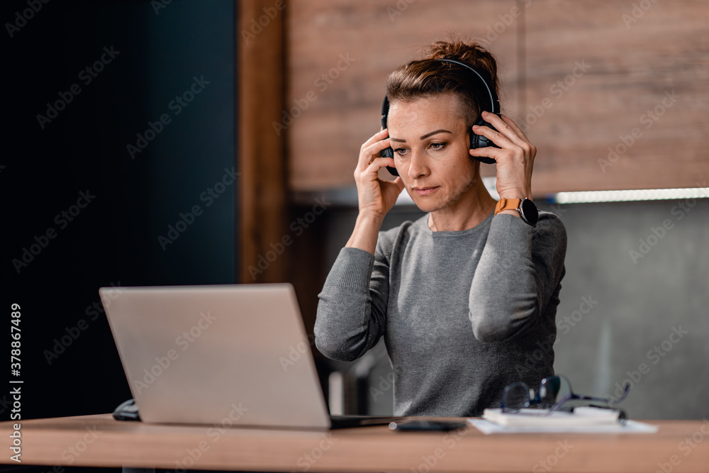 Woman putting on a headset and preparing for a conference call Woman putting on a headset and preparing for a conference call