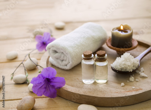 coconut oil and massage oil with spa salt  candle  towel on wooden background.