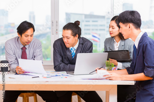 Business People Analyzing Statistics Financial Concept - Group of young confident business people analyzing data using computer in thailand.