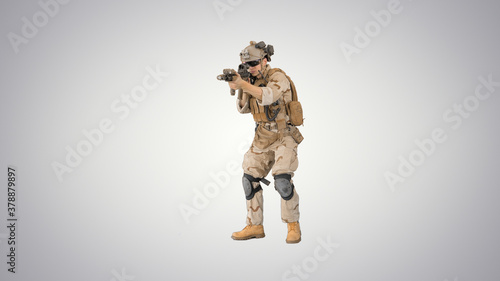 Armed marine soldier with assault rifle walking by aiming on gra