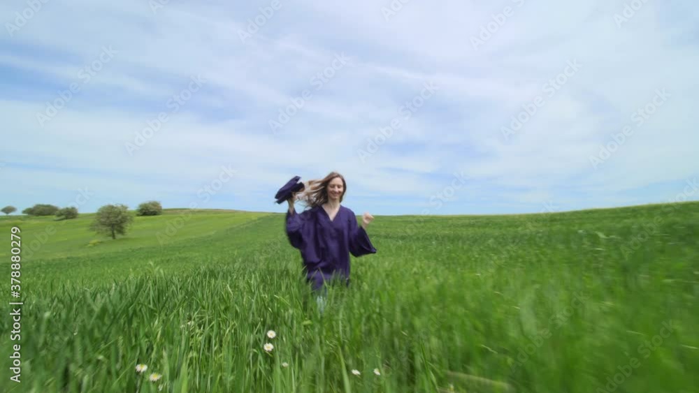 Graduation girl running alone in a green field with red tulip, throwing the cap in the air. Virtual graduation and social distancing concept. Graduation girl running alone in a green field with red tulip, throwing the cap in the air. Virtual graduation and social distancing concept.