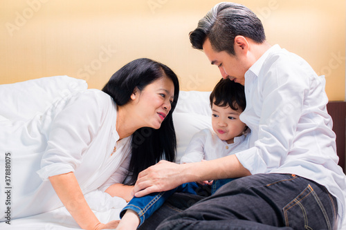 Sad little child, boy, hugging his Pregnant mother and Father on bed at home. Asian family © shine