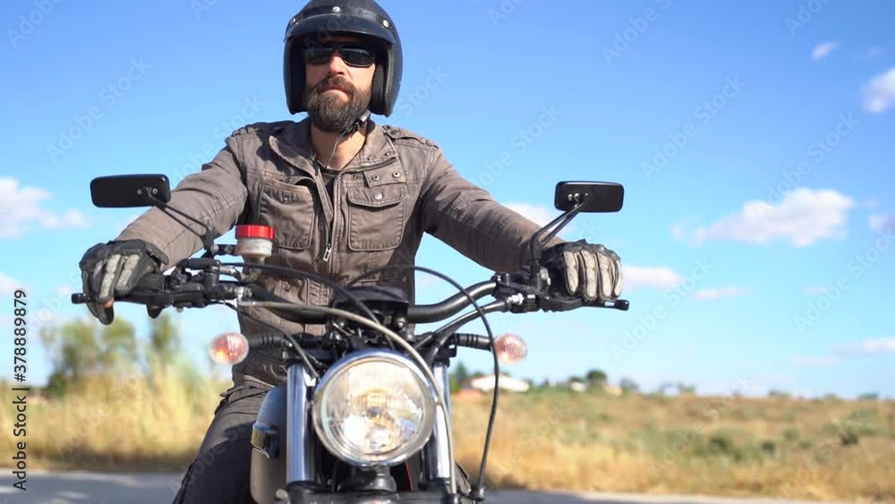 Dressed adult man with beaded sitting on motorbike ready for a ride on a sunny day Dressed adult man with beaded sitting on motorbike ready for a ride on a sunny day