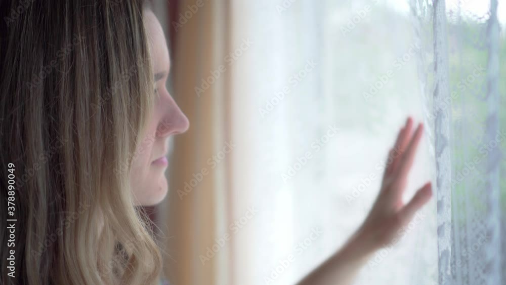 Girl longingly places hand on inside of window while looking outside, close up Girl longingly places hand on inside of window while looking outside, close up